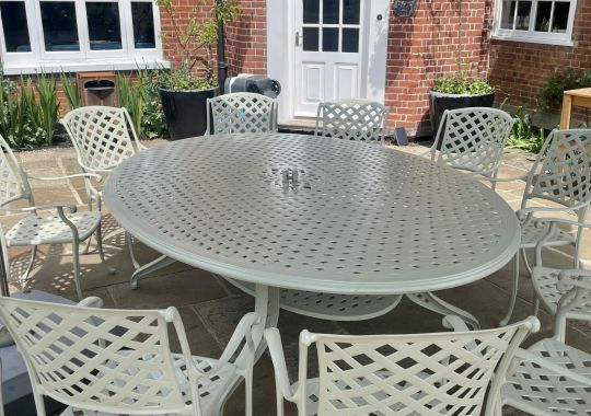 Spacious white outdoor dining set with a large round table and chairs, restored by Blast Spray Polish